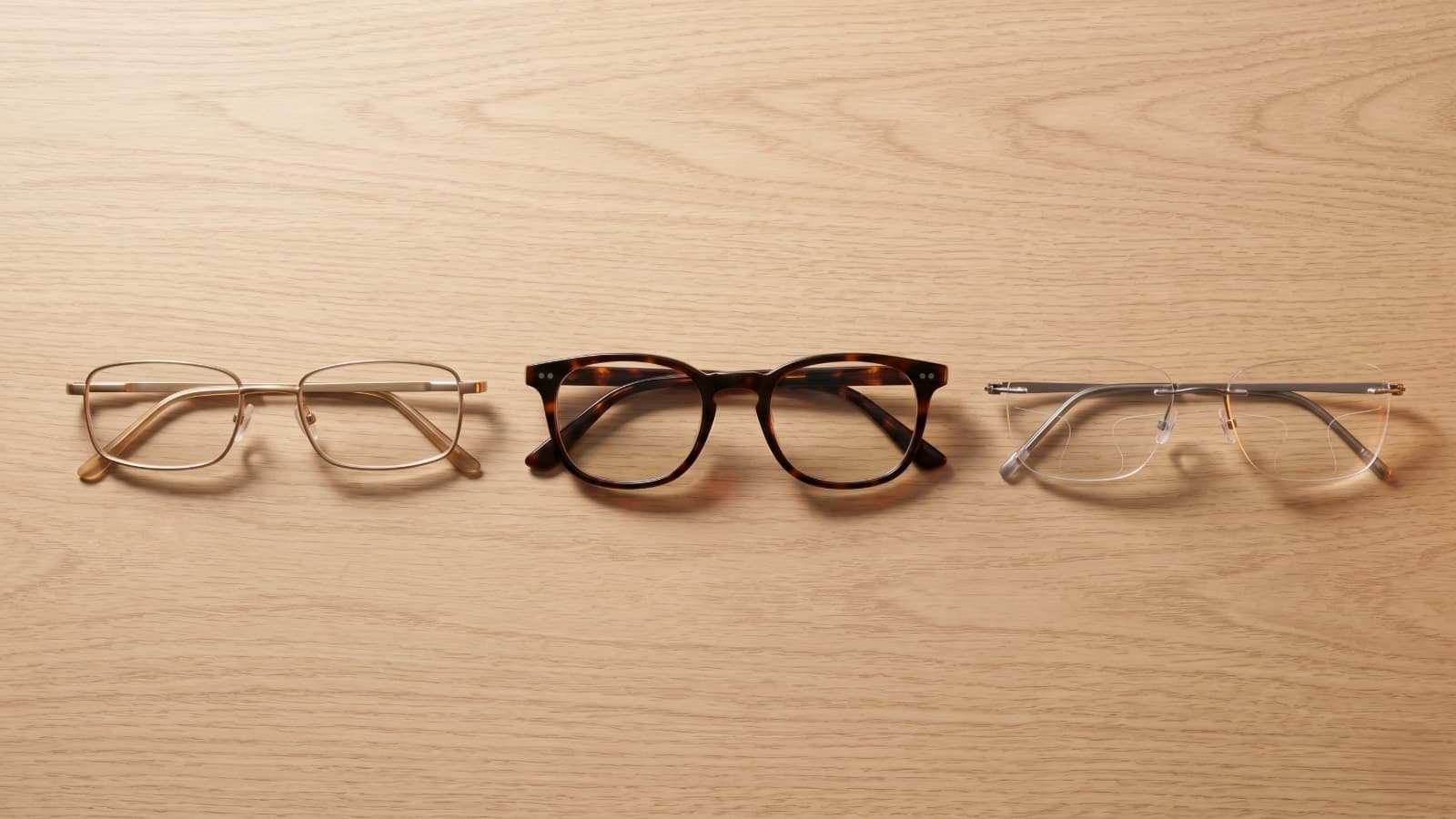 Tres pares de anteojos sobre una mesa: de lectura, clásico y multifocal progresivo, las opciones para corregir la presbicia